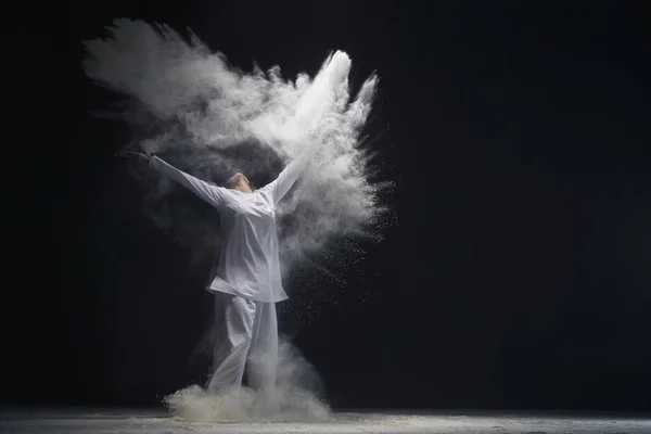 Toz bulutu içinde beyaz gömlek ve pantolon giyen adam — Stok fotoğraf