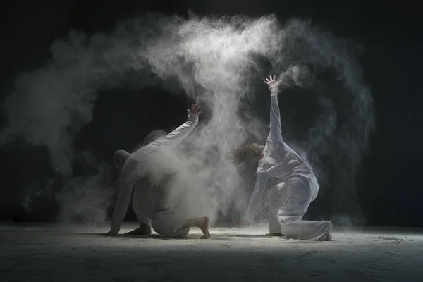 Two male doing yoga in dust cloud in dark room — Stock Photo, Image
