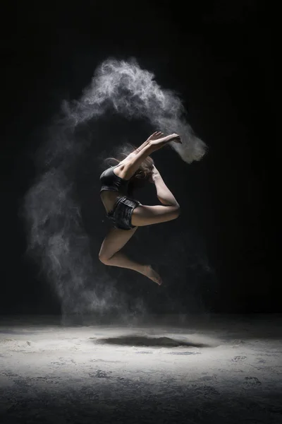 Femme en vêtements de sport sautant dans la poussière vue nuage — Photo