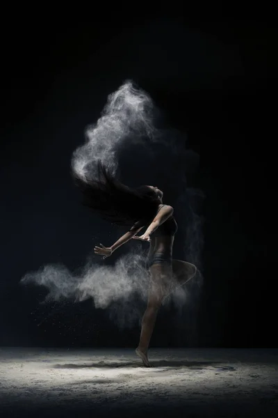 Brunette jumping gracefully in dust cloud view — Stock Photo, Image