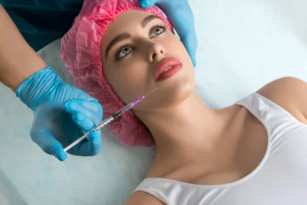 Girl in a disposal cap at lip beauty injection — Stock Photo, Image