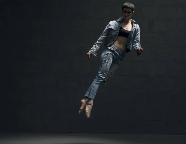 Девушка в джинсах грациозно прыгает в темноте — стоковое фото