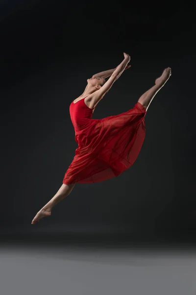 Slim girl jumping gracefully in the dark shot — Stock Photo, Image