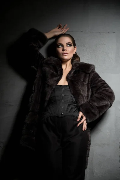 Gorgeous brunette in fur coat in the dark — Stock Photo, Image