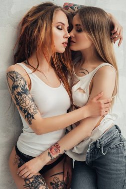 Atış duvara kucaklayan dövmeli seksi kızlar