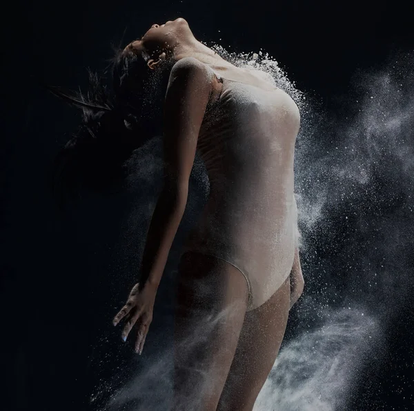 Giovane ragazza che salta nella nuvola di polvere bianca in studio — Foto Stock