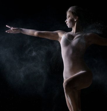 Dansçı incelikle toz bulutu içinde atlama