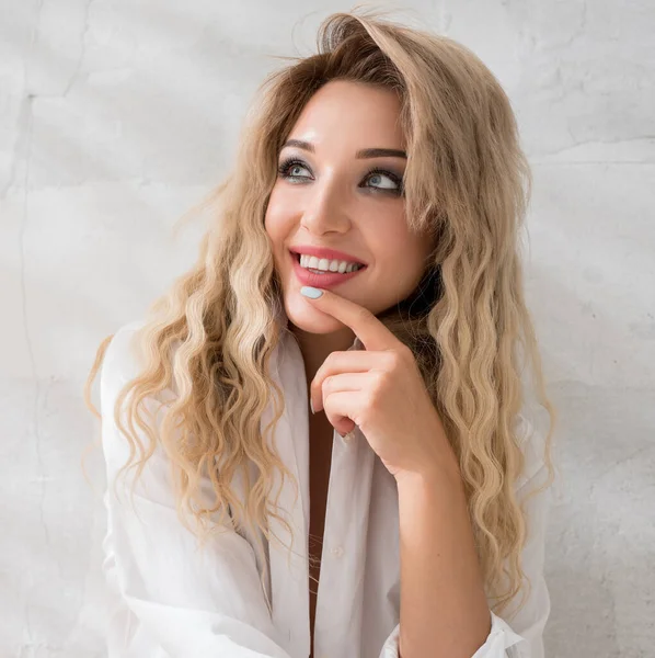 Sexy smiling blonde sitting on the floor in studio — Stock Photo, Image