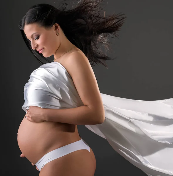 Чувственная беременная женщина позирует с трепещущей тканью — стоковое фото