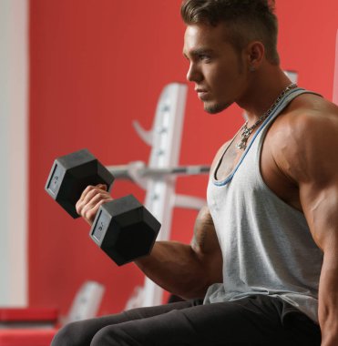 Yakışıklı adam spor salonunda dumbbells ile eğitim