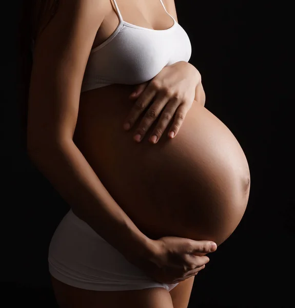Беременная молодая женщина позирует в нижнем белье в студии — стоковое фото