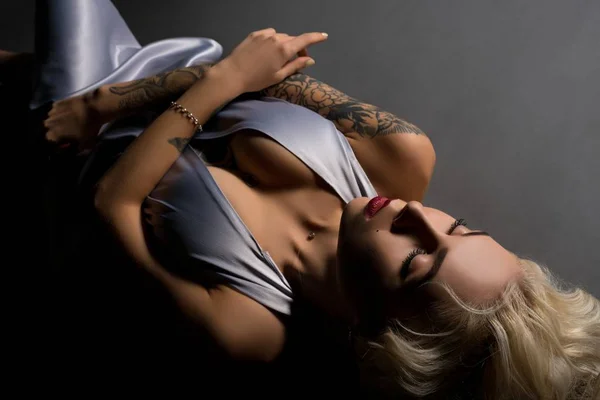 Beautiful tattooed blonde lying on the floor — Stock Photo, Image