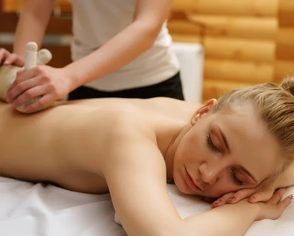 No spa. Menina relaxa durante a massagem com sacos de sal — Fotografia de Stock