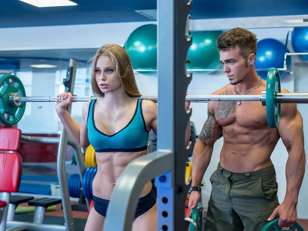 Trainer insures girl doing squats with barbell — Stock Photo, Image