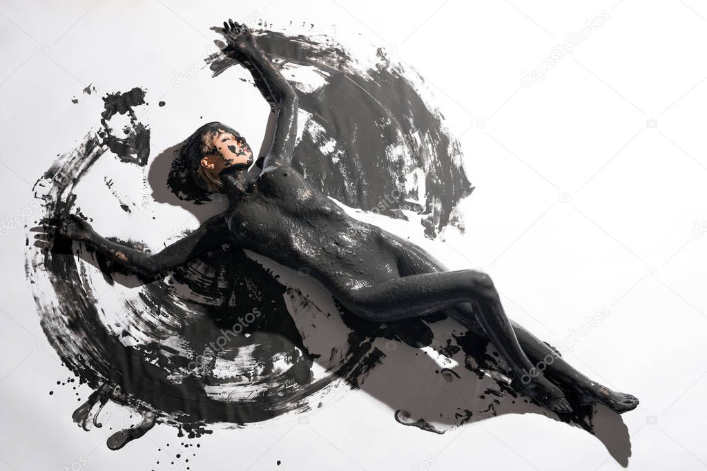 Nude girl in black color paint high angle view