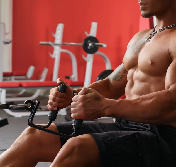 En el gimnasio. Sexy sin camisa chico ejercitando en simulador —  Fotos de Stock