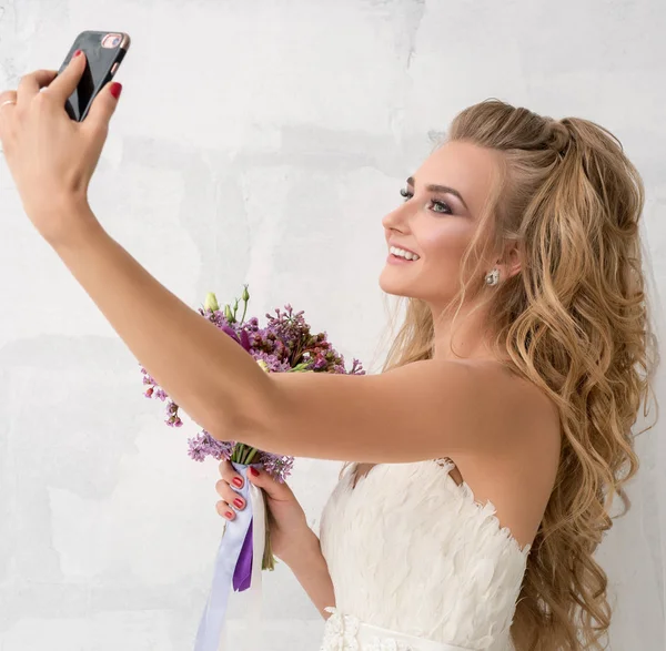 Junge Braut mit Blumenstrauß macht Selfie im Studio — Stockfoto