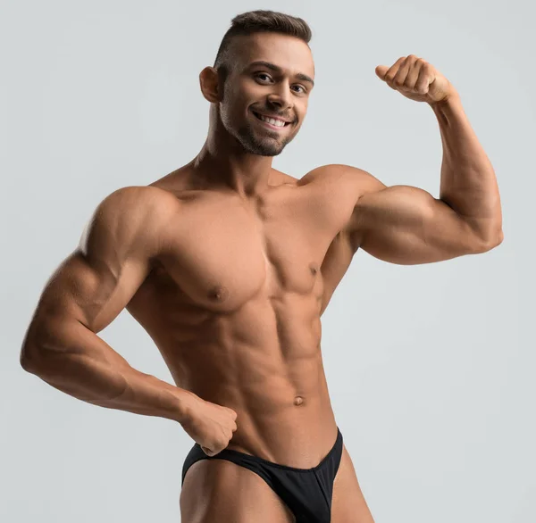 Atleta muscular de pelo oscuro disparado contra la pared gris — Foto de Stock