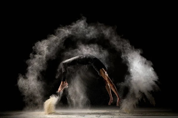 Male gymnast jumping in dust cloud profile view — Stok fotoğraf