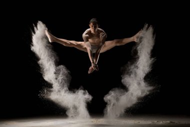 Male gymnast jumping in dust cloud view