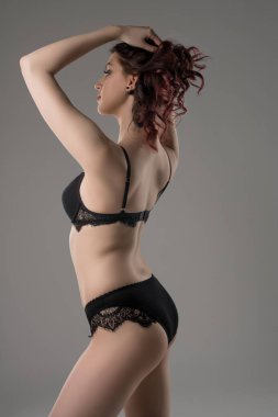 Young brunette in black lace lingerie profile view