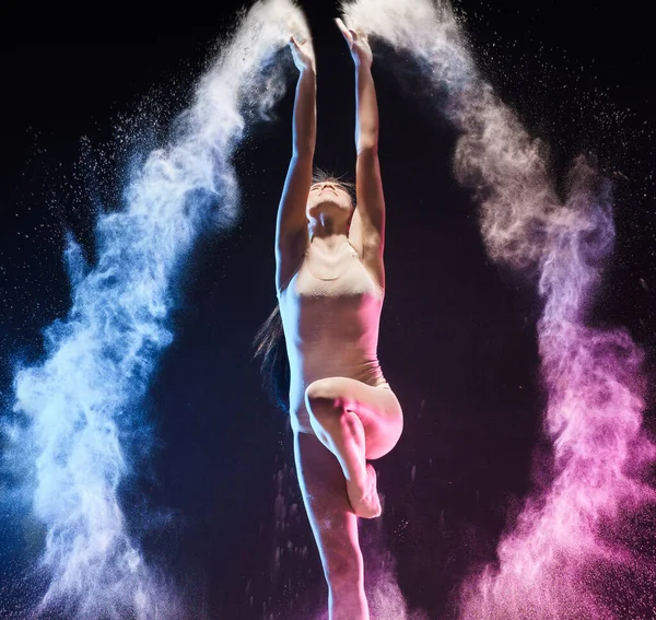 Giovane ragazza streching in salto nel colore nube di polvere — Foto Stock