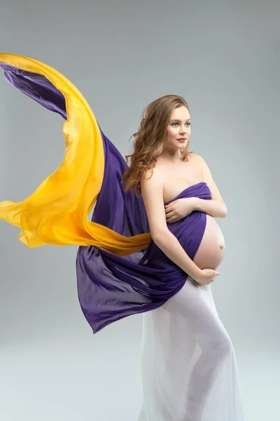 Mujer embarazada cubriendo el pecho y tocando el vientre —  Fotos de Stock