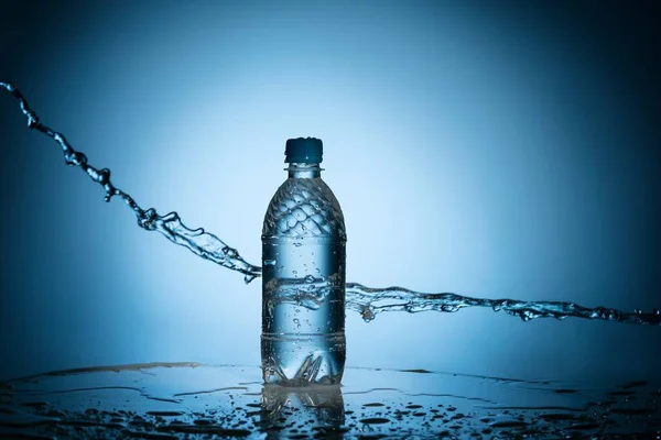 Goteo de agua limpia cerca de botella de plástico transparente — Foto de Stock