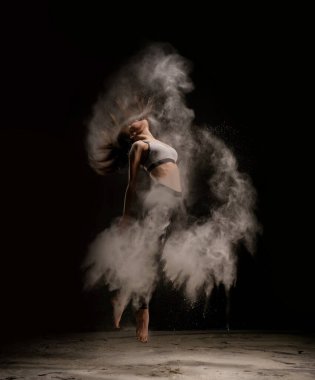 Toz bulutları içinde dans eden genç bir kadın