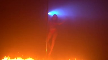 İç çamaşırlı esmer, ateşte striptiz yapıyor.