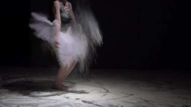 Tutu içinde zarif bir dansçı ve karanlıkta toz.