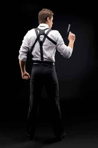 Style Muscular man with gun stand back to camera in dark — Stock Photo, Image