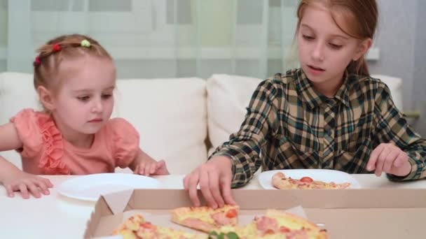 Menina dando um pedaço de pizza para sua irmã mais nova, vídeo — Vídeo de Stock