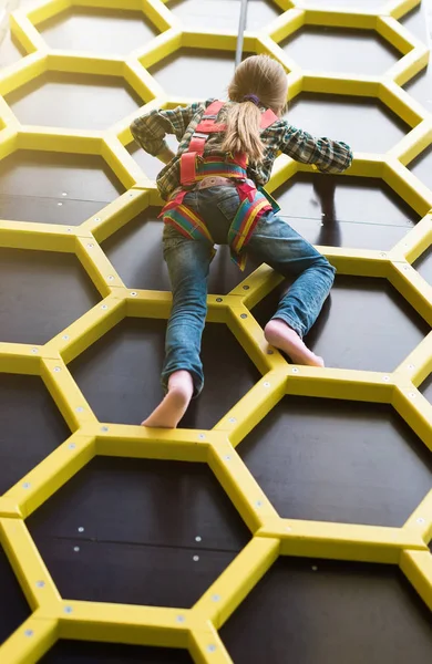 Kleines Mädchen klettert barfuß an Seilen die Wand hinauf — Stockfoto