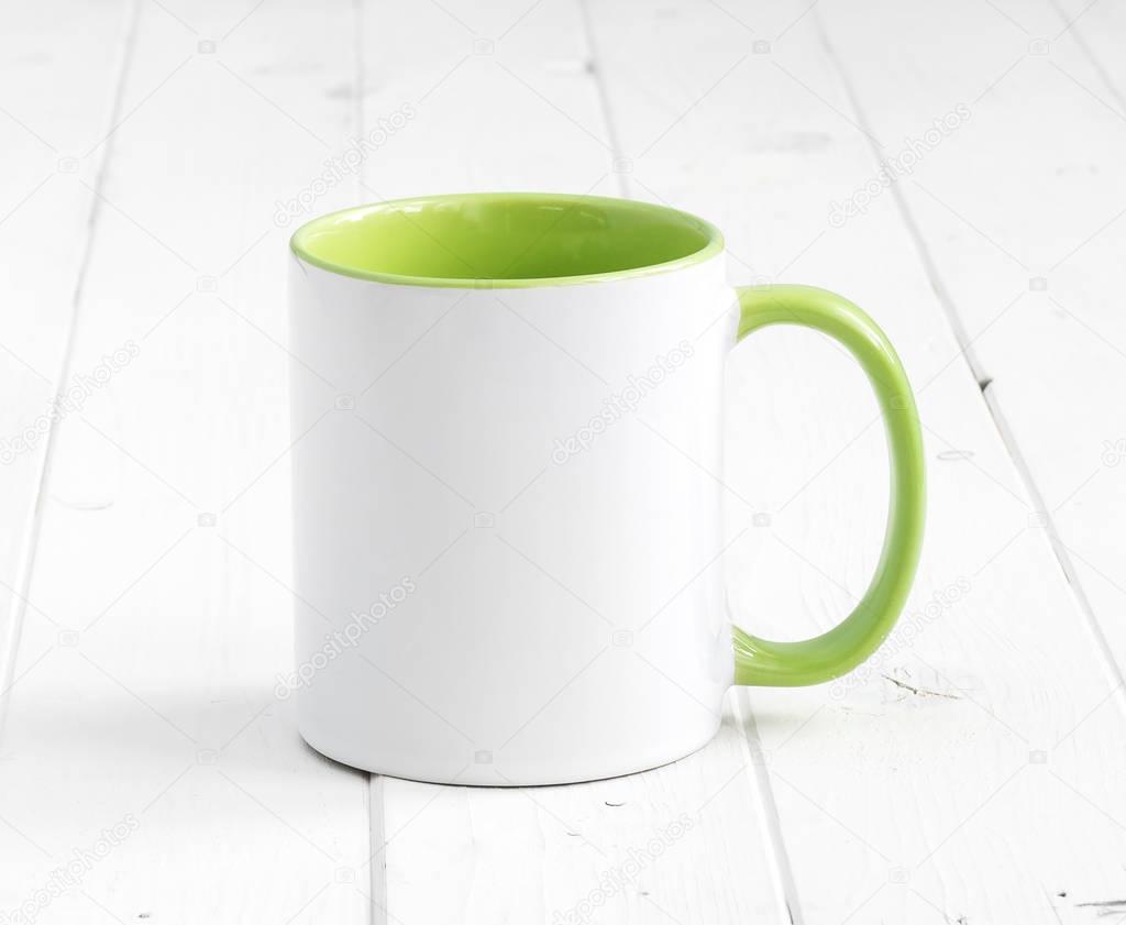 white cup with green inside on wooden background