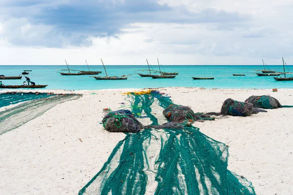 大渔网躺在非洲海滩上用小船靠近岸边 — 图库照片