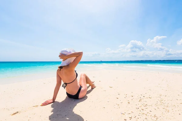 Girl in hat sitting on beautiful beach — Stock Photo, Image