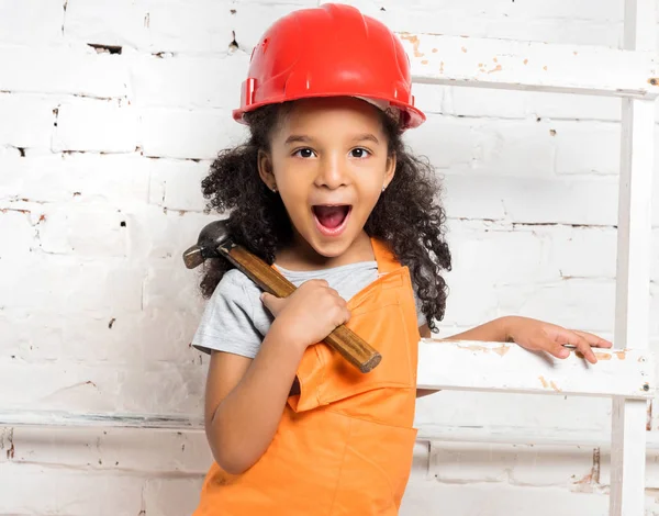 Little girl in helmet with hammer and screwdriver — Stock Photo, Image