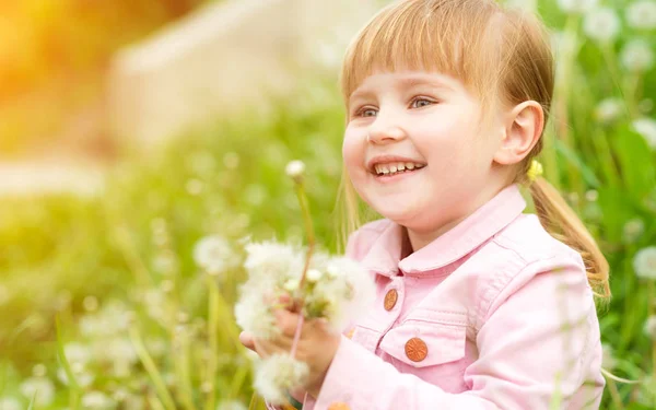 Sorridente bambina con denti di leone — Foto Stock