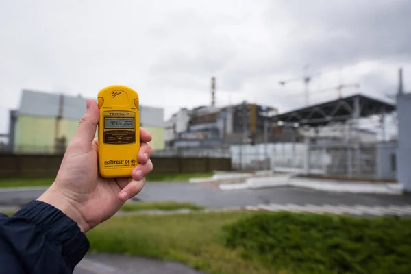 Radiometer in hand with fourth reactor on the background — Stock Photo, Image