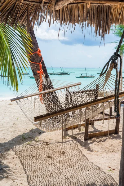 Beautiful landscape with hammock hanging on palm and boats in ocean on the background — Stock Photo, Image