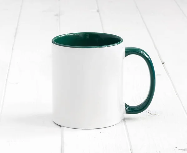 White cup with green inside on wooden background — Stock Photo, Image