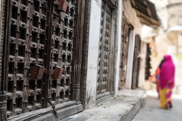 Zanzíbar calle de la ciudad con puertas de hierro y wooman a pie — Foto de Stock