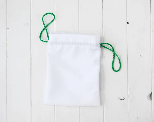 White fabric gift sac on dark wooden background — Stock Photo, Image