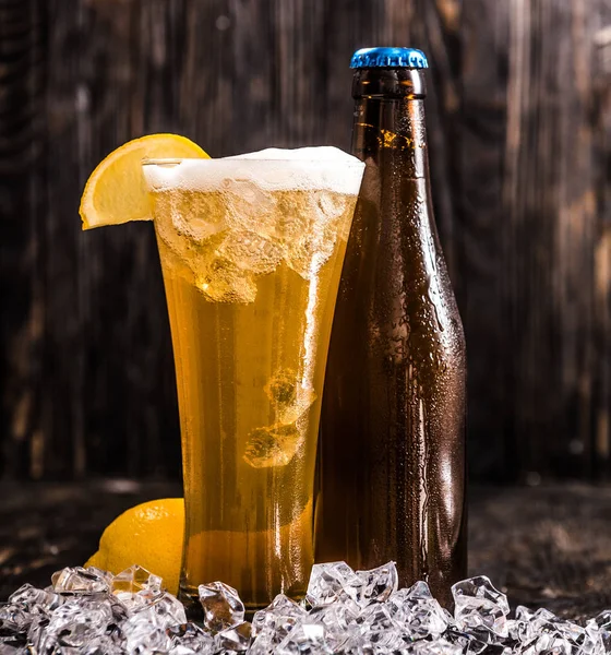 Garrafa e um copo de cerveja com gelo e limão — Fotografia de Stock