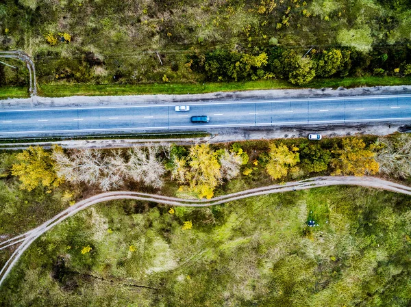 Pista de asfalto com árvores e estrada rolada de um lado — Fotografia de Stock