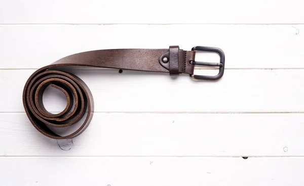 Cinturón de cuero marrón retorcido sobre fondo de madera — Foto de Stock