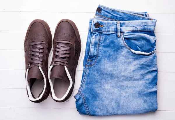 Zapatos masculinos nuevos y jeans en mesa de madera — Foto de Stock