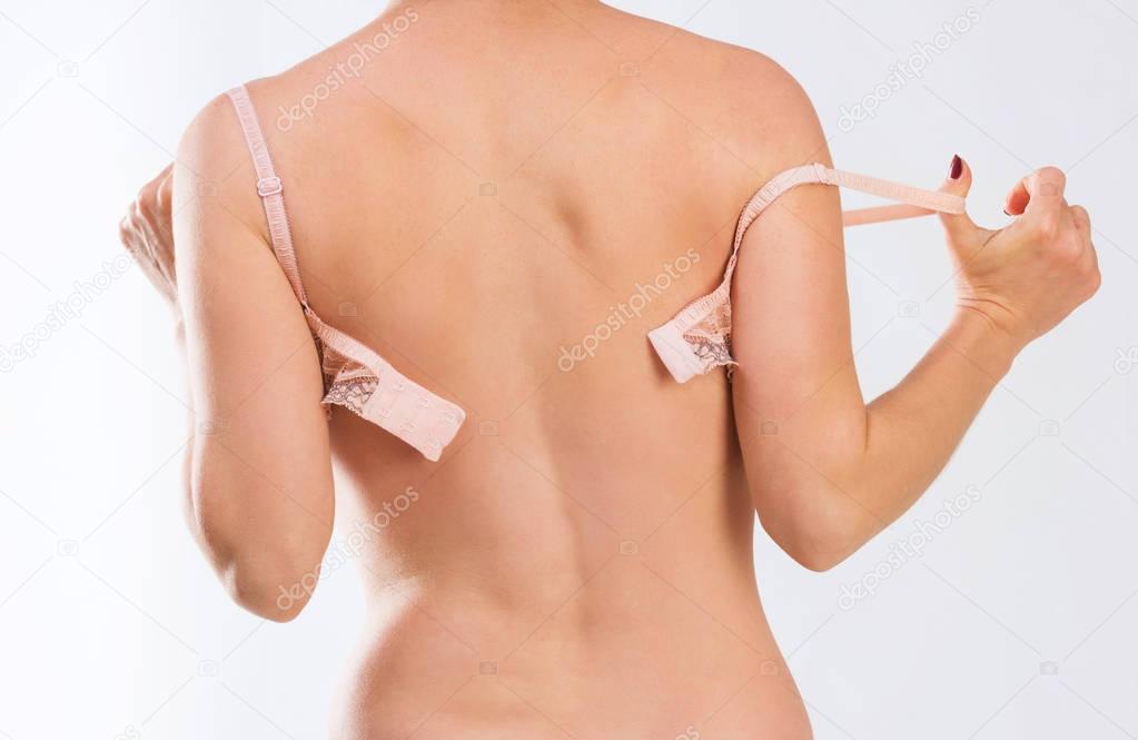 Woman in lingerie taking off her bra, backshot