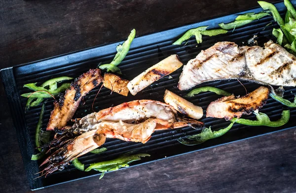 Appetizing grilled seafood on black plate — Stock Photo, Image